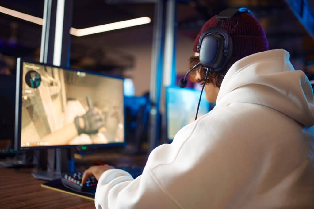 Young gamer in headset play shooter in game club